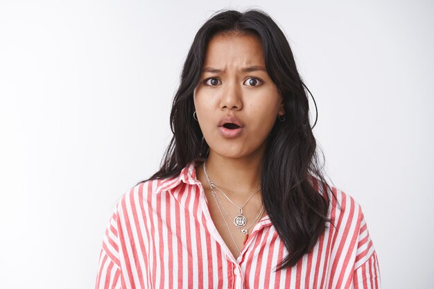 Concerned female friend hearing disturbing news feeling empathy and pitty standing worried and upset frowning open mouth, feeling sorry for terrible situation happening standing against white wall