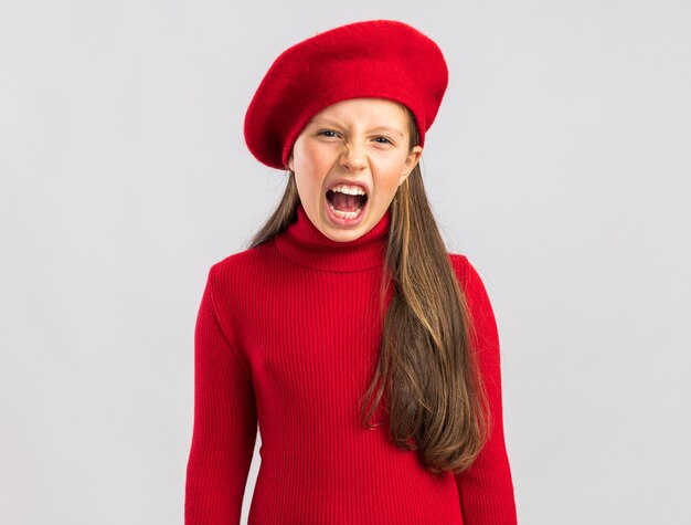 Concerned little blonde girl wearing red beret looking at front and scream isolated on white wall with copy space