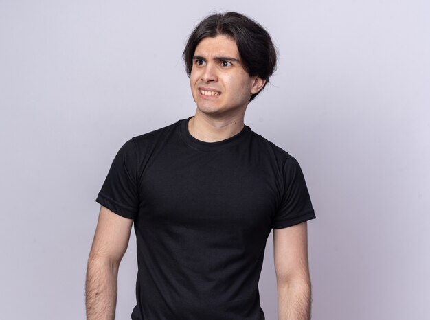 Concerned looking at side young handsome guy wearing black t-shirt isolated on white wall