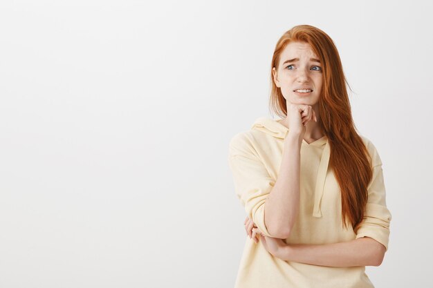 Concerned redhead girl panicking, looking left overwhelmed