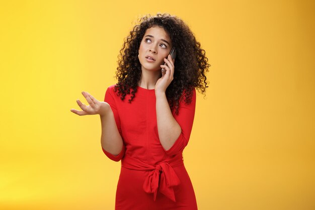 Concerned and sad female friend telling details of bad situation happened on mobile phone discussing upset things with unhappy face gesturing with raised hand holding smartphone pressed to ear.