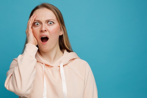 Free photo concerned young blonde woman keeping hand on face