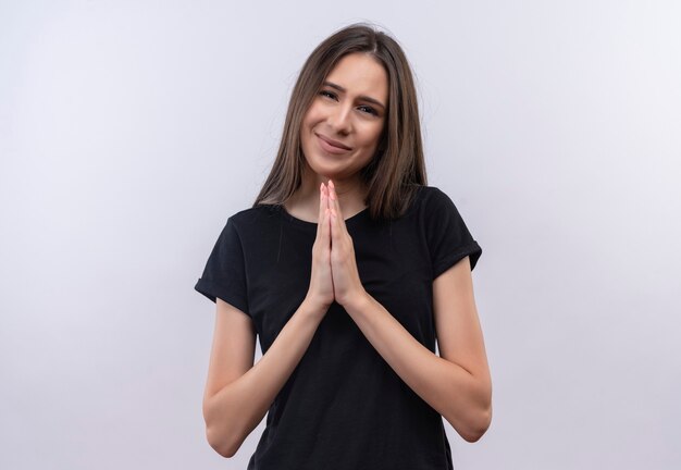 concerned young caucasian girl wearing black t-shirt showing pray gesture on isolated white wall