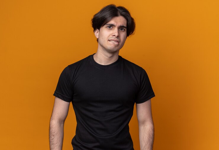 Free Photo concerned young handsome guy wearing black t-shirt bites lips isolated on orange wall