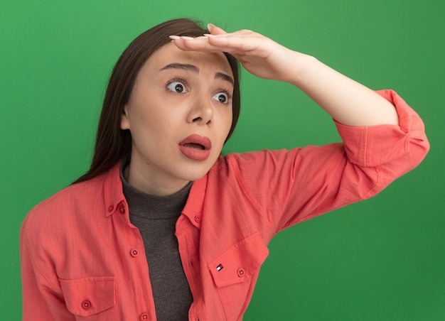 Free photo concerned young pretty woman looking at side into distance keeping hand on forehead isolated on green wall