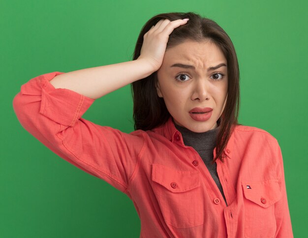 Free photo concerned young pretty woman putting hand on head looking at front isolated on green wall