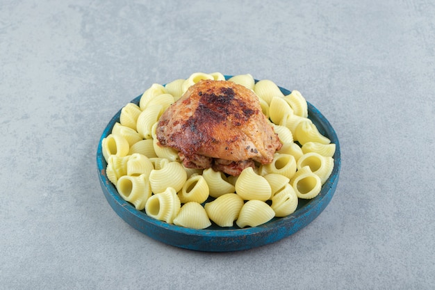 Conchiglie pasta and grilled chicken on blue plate