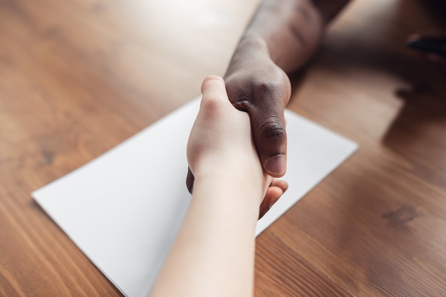 Conclusion of contract, friendship. Close up of african-american male and caucasian female hands shaking. Concept of business, finance, job. Copyspace for ad. Education, communication and freelance.