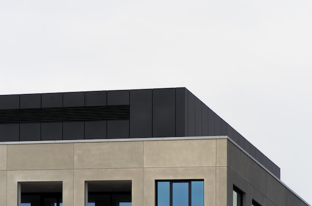 Foto gratuita un edificio di cemento con finestre a specchio sotto il cielo limpido