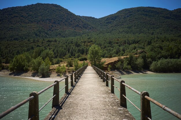 Concrete pedestrian bridge on a bay among green hills