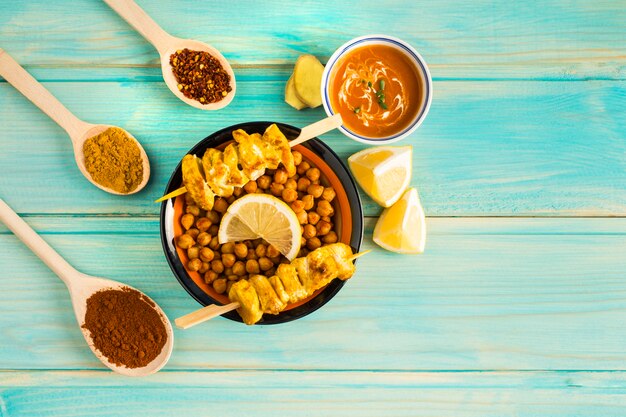 Condiments around chickpea and chicken kebab