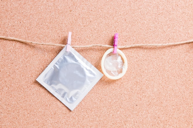 콘돔과 포장은 메모, 안전한 섹스 개념을 위한 코르크 사무실 칠판의 배경에 대해 종이 실에 있는 작은 나무 옷핀에 매달려 있습니다.