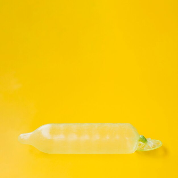 Condom filled with water on yellow background