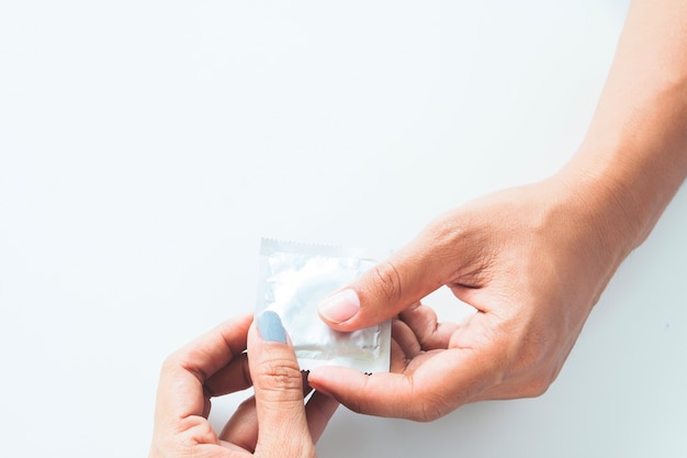 Презерватив в мужской руке и женской руке, дать презерватив безопасной концепции пола на белом фоне