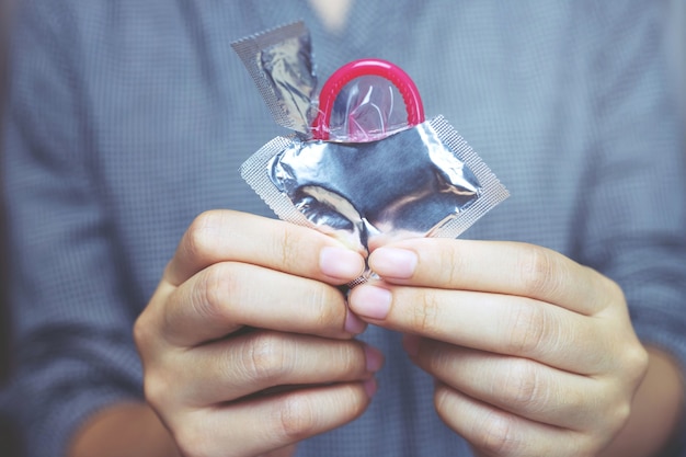 Condom ready to use in female hand, give condom safe sex concept on the bed prevent infection.