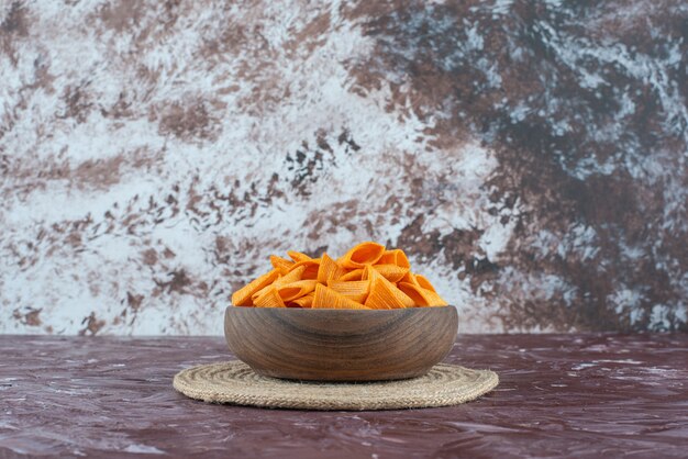 Cone chips in a bowl on trivet on marble. 