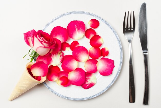 Free photo cone and petals on plate near utensils