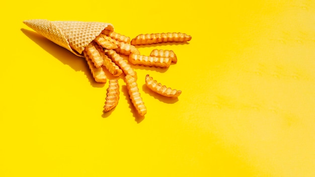 Free photo cone with french fries on yellow background