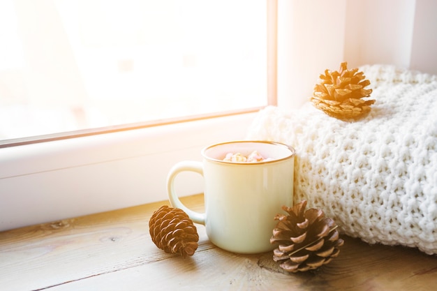 Cones and hot chocolate near scarf and window