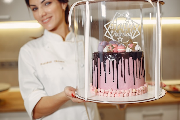Бесплатное фото Кондитер в униформе украшает торт