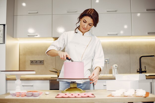 制服を着た菓子職人がケーキを飾る