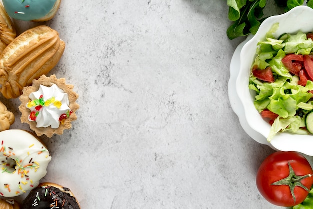 Confectionery food and healthy vegetable salad on rough surface