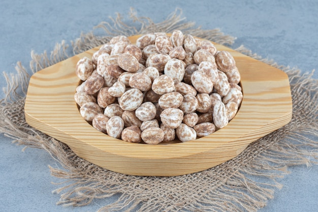 Confectionery in the wooden plate, on the trivet, on the marble table. 