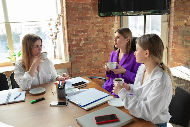 Conference. Young caucasian business woman in modern office with team. Meeting, tasks giving. Women in front-office working. Concept of finance, business, girl power, inclusion, diversity, feminism.
