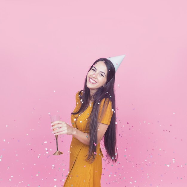 Confetti falling over the smiling young woman holding champagne flute