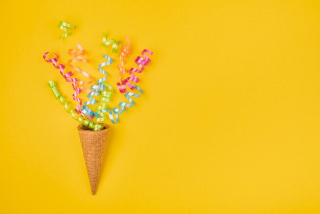 Confetti in ice-cream cone with copy-space on yellow background