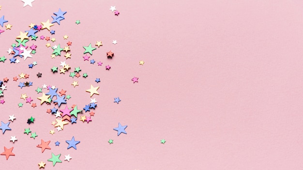 Бесплатное фото Конфетти звезды на розовом фоне с копией пространства