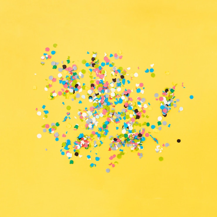 Free Photo confetti on yellow background after the party