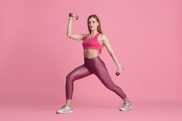 Fiducia. bella giovane atleta femminile che pratica in studio, ritratto rosa monocromatico.