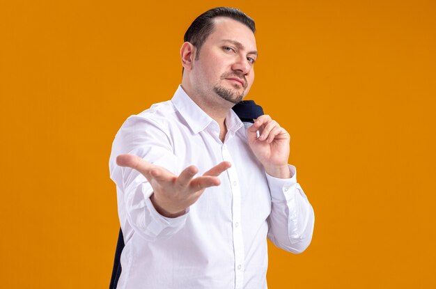 Confident adult slavic businessman holding jacket on his shoulder and keeping hand open 