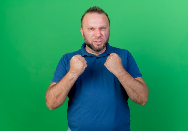 Free photo confident adult slavic man looking  clenching fists isolated on green wall