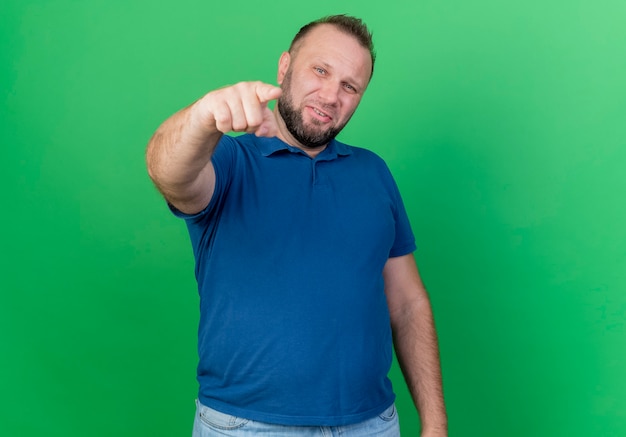 Confident adult slavic man pointing  isolated on green wall with copy space