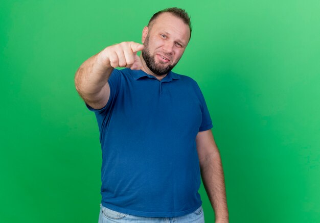 Confident adult slavic man pointing  isolated on green wall with copy space