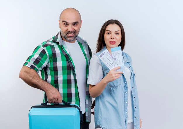 Confident adult traveler couple man holding suitcase and woman holding travel tickets both looking