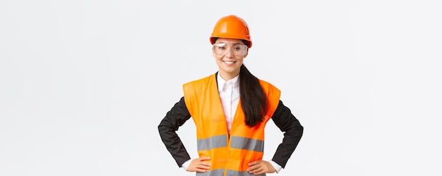 無料写真 安全ヘルメット保護メガネの自信を持ってアジアの女性建築家建設エンジニアは、作業の白い背景の結果に満足して笑顔で検査のために建物のエリアに入る準備ができています