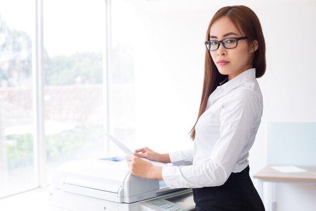 Free Photo confident asian woman using photocopier in office