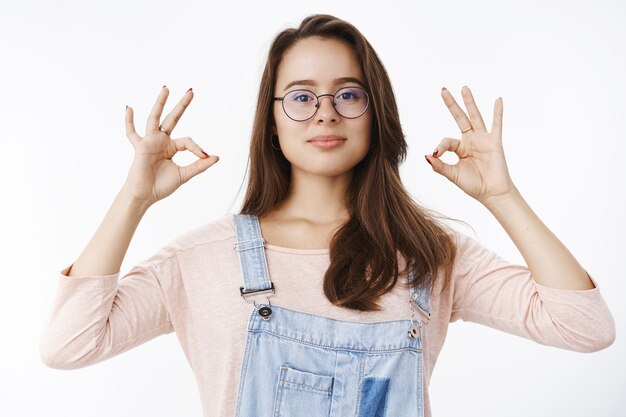 Free photo confident assertive female professional in overalls and glasses assuring work going great, showing okay gesture with self-assured expression, smiling satisfied, liking product.