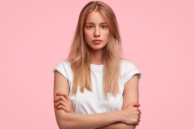 Confident attractive young European woman keeps hands crossed, looks seriously