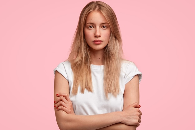 Confident attractive young European woman keeps hands crossed, looks seriously