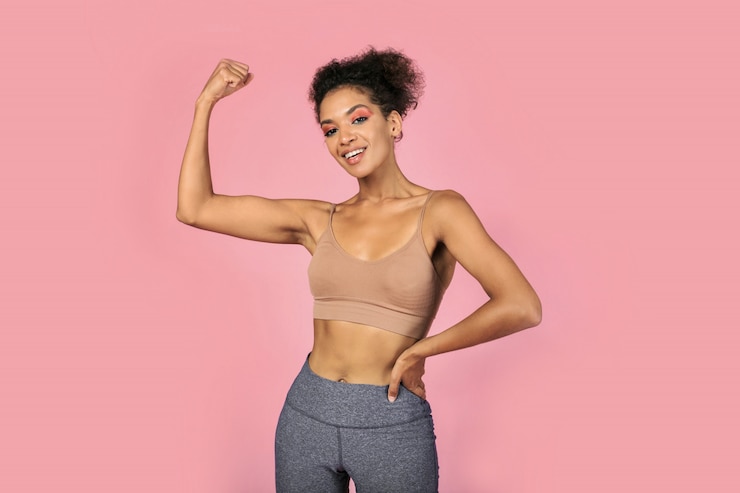Free Photo confident black woman showing muscular and power . african female in styloish sportwear posing over pink background .