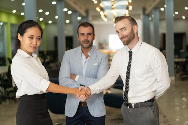 Confident business people shaking hands in office lobby