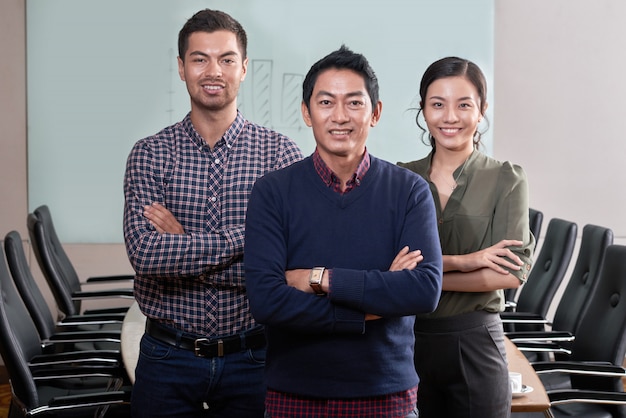 Free photo confident business team standing arms folded in the conference room