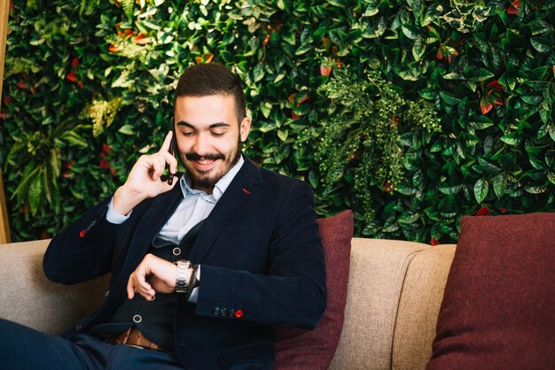 Confident businessman checking time and talking phone