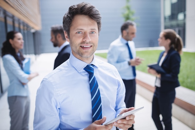 Free photo confident businessman holding digital tablet outside office building