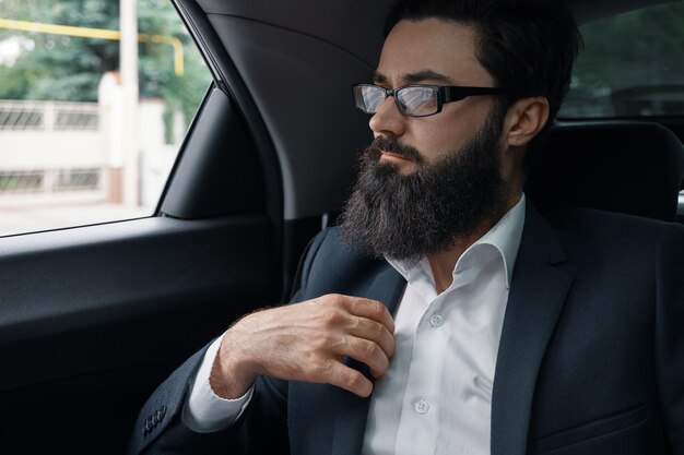 Confident businessman sitting on the car back sit