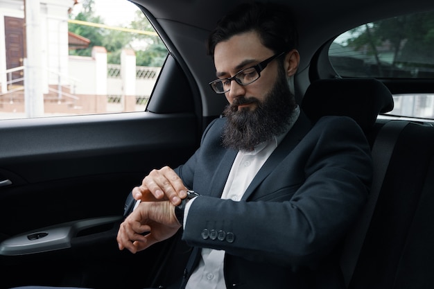 Confident businessman sitting on the car back sit